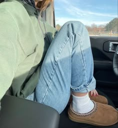 a woman sitting in the passenger seat of a car with her feet on the floor