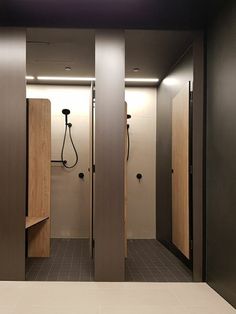 an empty bathroom with two stalls and a shower head in the wall, along with tiled flooring