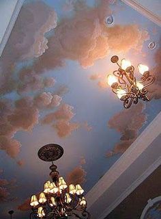 a chandelier hanging from the ceiling in a room with clouds painted on it