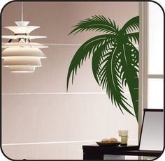 a laptop computer sitting on top of a desk next to a palm tree wall decal