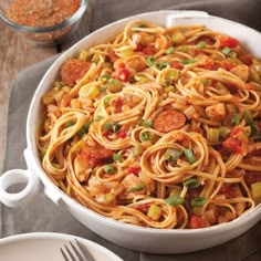 a white bowl filled with pasta and vegetables on top of a table next to a fork