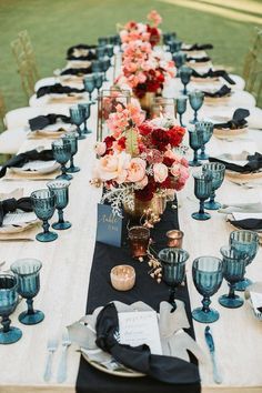 a long table is set with blue dishes and silverware