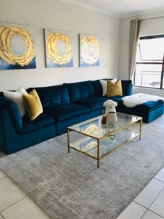 a living room with blue couches and two paintings on the wall