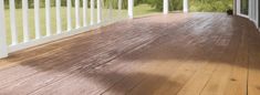 an empty porch with white railings and wood flooring on the side of it