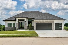 a large house with two garages and grass in the front yard on a sunny day