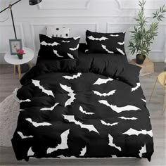 black and white bedding with bats on it in a room next to a plant