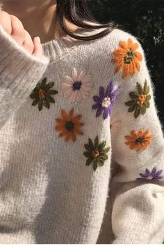 a close up of a person wearing a sweater with flowers on it