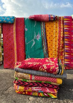 colorful fabrics are stacked on top of each other in the middle of a parking lot