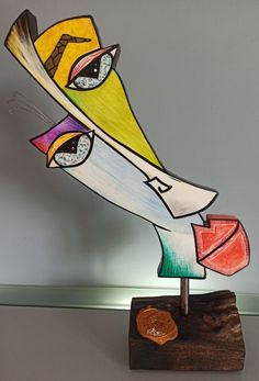 a colorful sculpture on a wooden stand with a heart in the center and eyes drawn on it