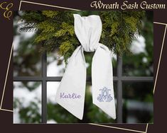 a white scarf hanging on a window sill with the name kallelie written on it