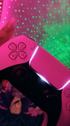 a person holding a pink video game controller in front of a green and purple background