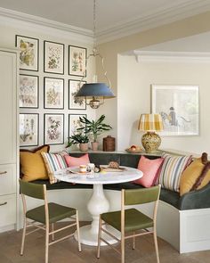 a white table with colorful pillows and some pictures on the wall in a living room