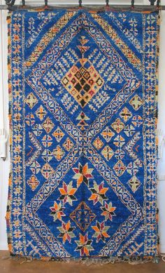 a blue and orange rug hanging on a wall