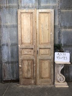 two wooden doors sitting next to each other in front of a metal wall with a sign on it