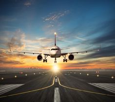 an airplane taking off from the runway at sunset