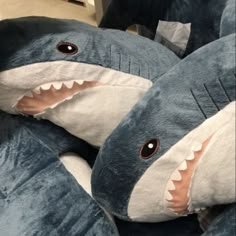 three stuffed shark toys are laying on the floor with their mouths open and eyes wide open