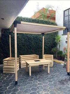 a wooden table and bench sitting under a pergolated roof