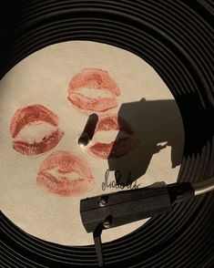 a record with lipstick drawn on it next to a pair of scissors and a pen