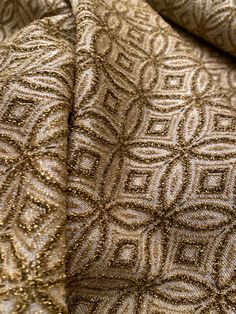 the fabric is gold and has intricate designs on it, as well as metallic thread