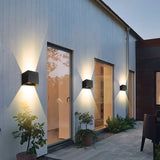 an outdoor patio with lights on the side of it and potted plants in front