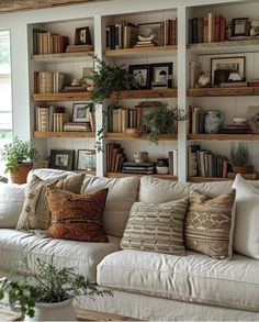 a living room filled with lots of white furniture and bookshelves covered in books