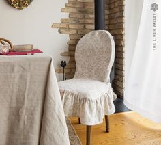 a white chair sitting next to a table with a cloth on it and a wooden floor