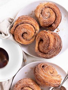 cinnamon rolls on plates next to a cup of coffee