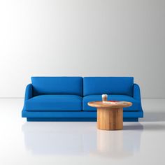 a blue couch sitting next to a wooden table on top of a white floor in front of a wall