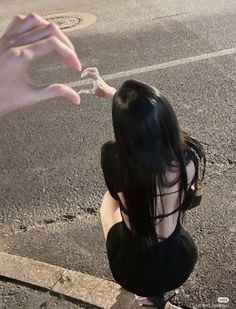 a woman is sitting on the curb with her hand reaching for something in front of her