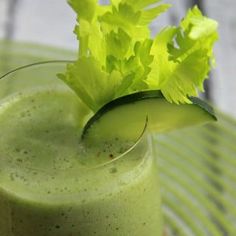 a green smoothie with cucumber garnish on top