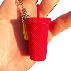 a hand holding a red cup with a straw in it and a chain around it