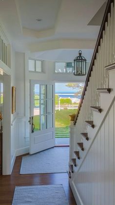 an entry way leading to a house with white walls and wood floors, along with a blue rug on the floor