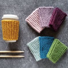 crocheted coffee cup cozyies and knitting needles on a gray surface with the lid off