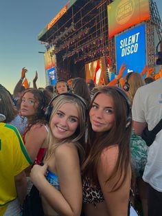 two young women standing next to each other in front of an audience at a music festival