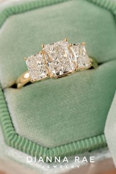 three stone diamond ring sitting on top of a green velvet cushion in a jewelry box