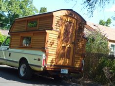 a truck is parked in front of a house with a dog sticking its head out the window