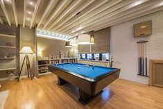 a pool table in the middle of a room with shelves and lamps on either side