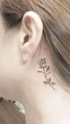 a woman's neck with a small rose tattoo on her left side behind the ear