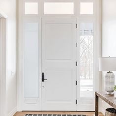 a white front door with two sidelights and a rug on the floor next to it