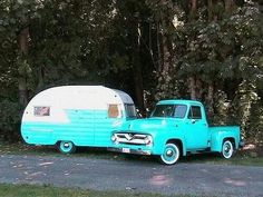 an old blue truck with a camper in the back parked next to it's trailer