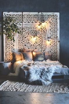 a bed with pillows, blankets and lights on the headboard is made from wood