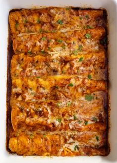 a casserole dish with meat, cheese and parsley in it on a white surface