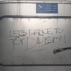 graffiti written on the side of a metal container that says, let's dance to joy division