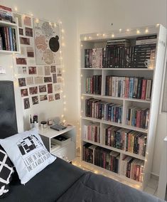 a bedroom with bookshelves and lights on the wall above the bed is lit up by fairy lights