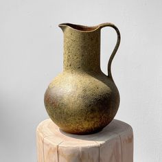 a brown vase sitting on top of a wooden stump