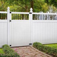 a white fence with flowers and bushes around it