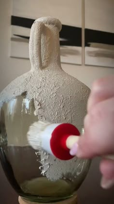 a person is painting a vase with white paint