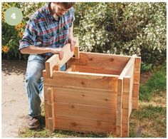 a man sitting on the ground next to a wooden planter box with his hands in it