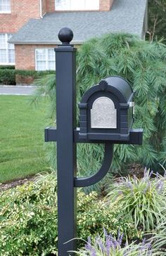 a black mailbox sitting in the middle of a flower bed next to a house