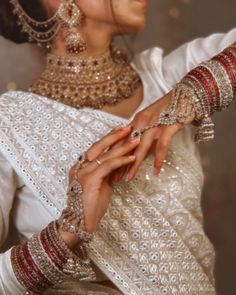 a woman in white dress with jewelry on her hands